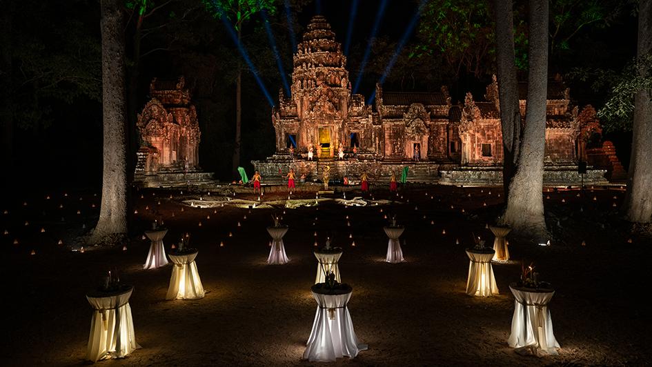 Thommanon Temple lit up at night, with candle-lit cocktail tables in front of the temple